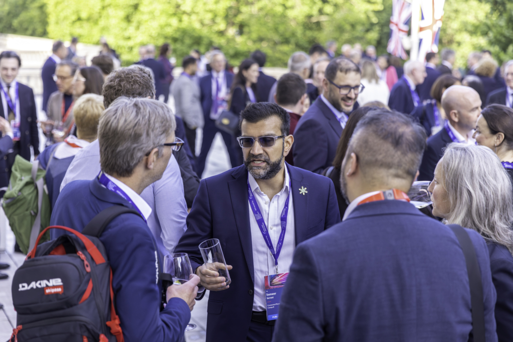 People pictured networking outside with a Union Jack flag and trees in the distance.