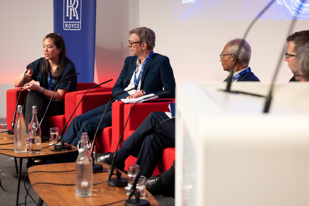Pictured are speakers in chairs with a Rolls Royce Banner behind them at the UK Global R&D and Science Summit