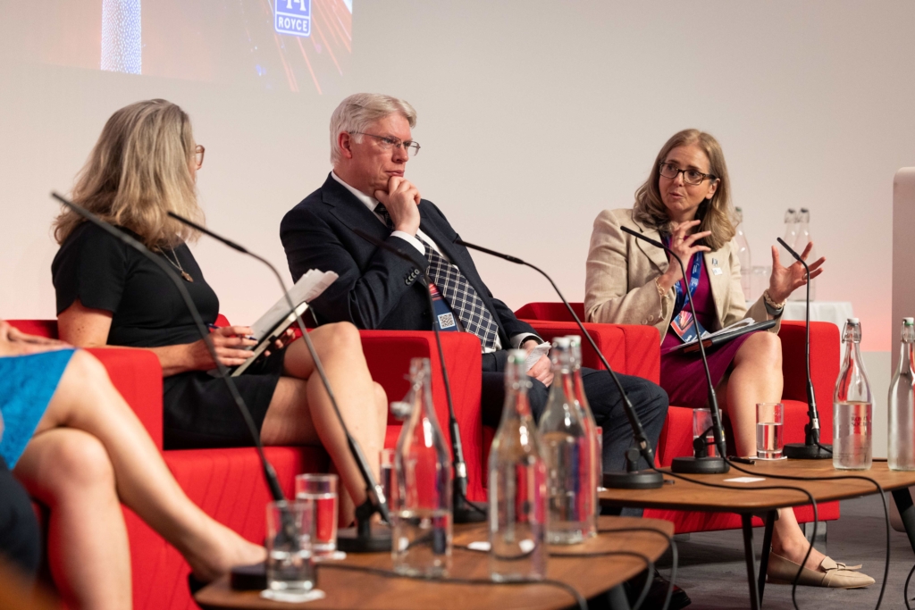 Image of people on a panel sat in red chairs.